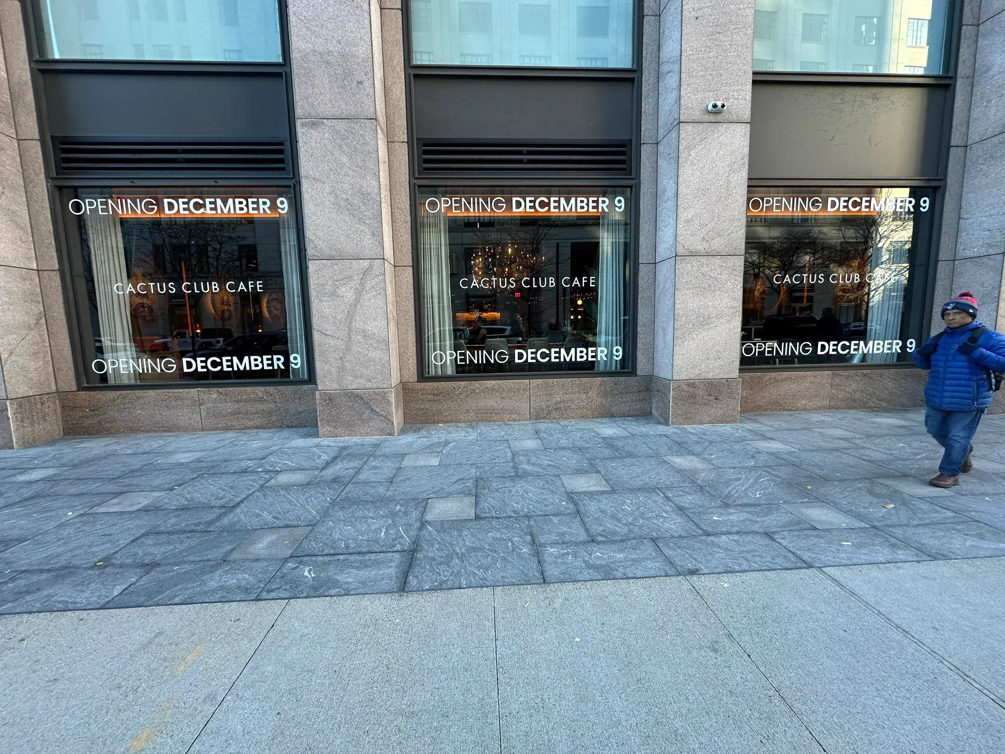 Three storefront bays with Opening December 9 Cactus Club Cafe vinyl lettering