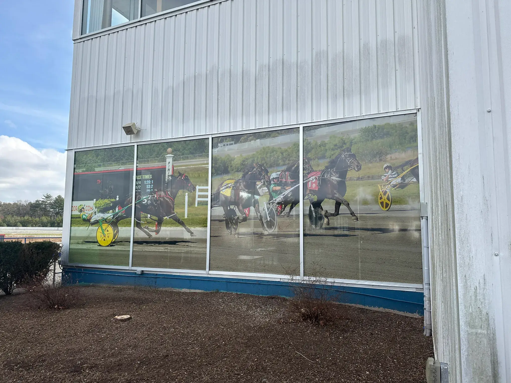 Four panel printed window graphic of harness racing horses on a metal building