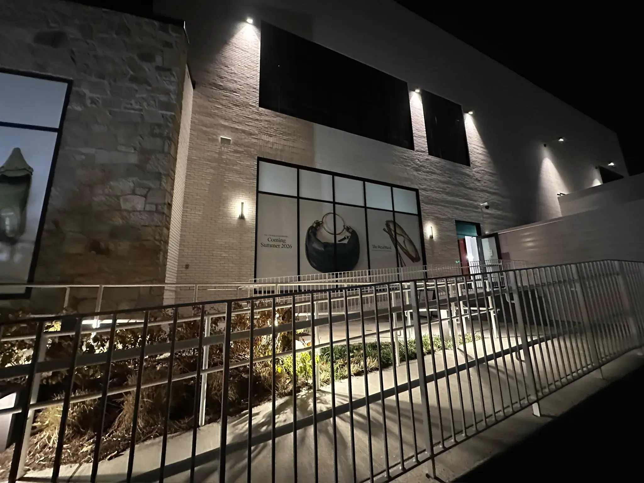The RealReal coming soon storefront graphic lit at night