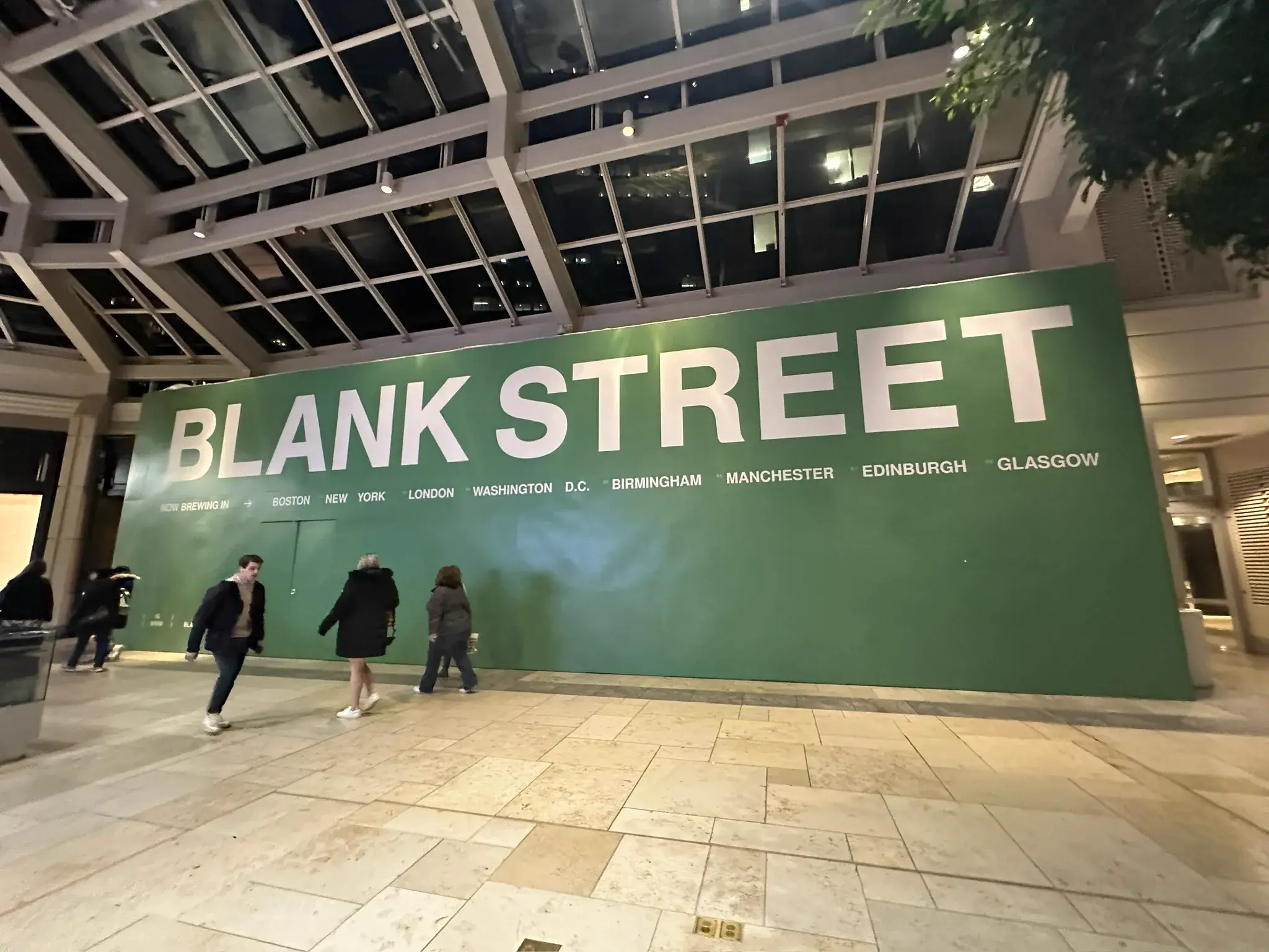 Green Blank Street hoarding in a glass-roofed shopping atrium