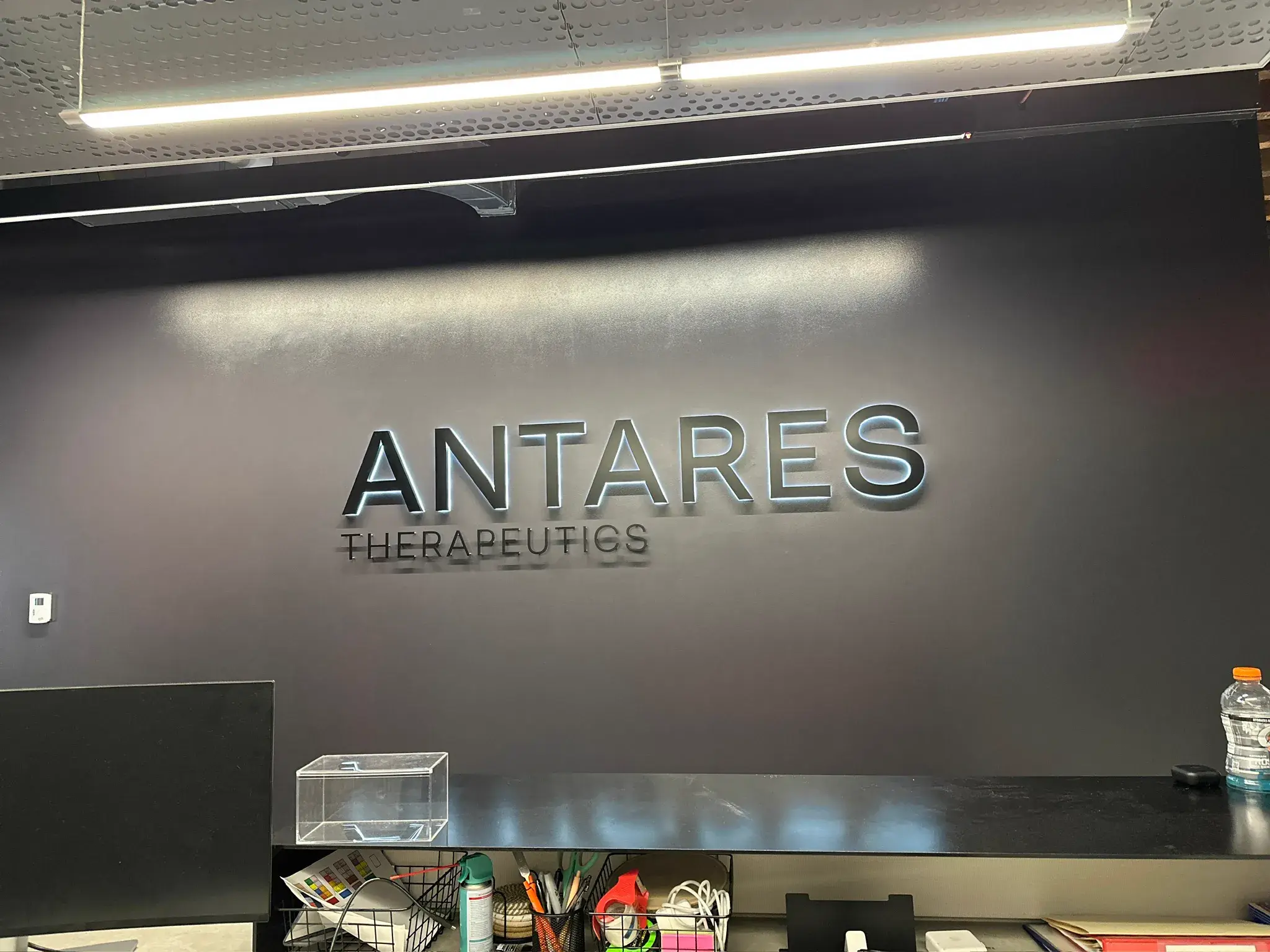 Backlit ANTARES THERAPEUTICS dimensional letters on a dark reception wall