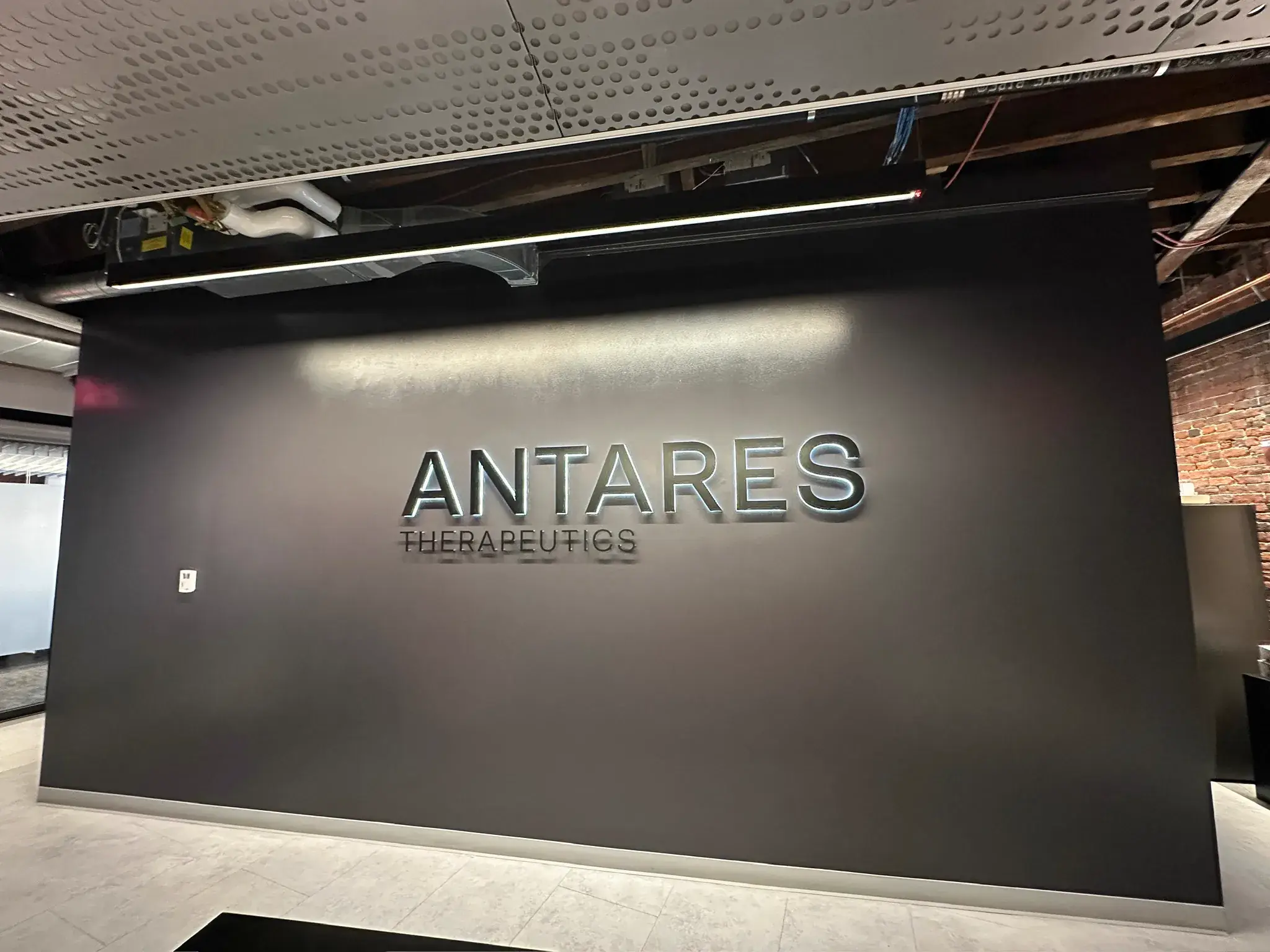 Angled view of the Antares Therapeutics sign wall next to exposed brick