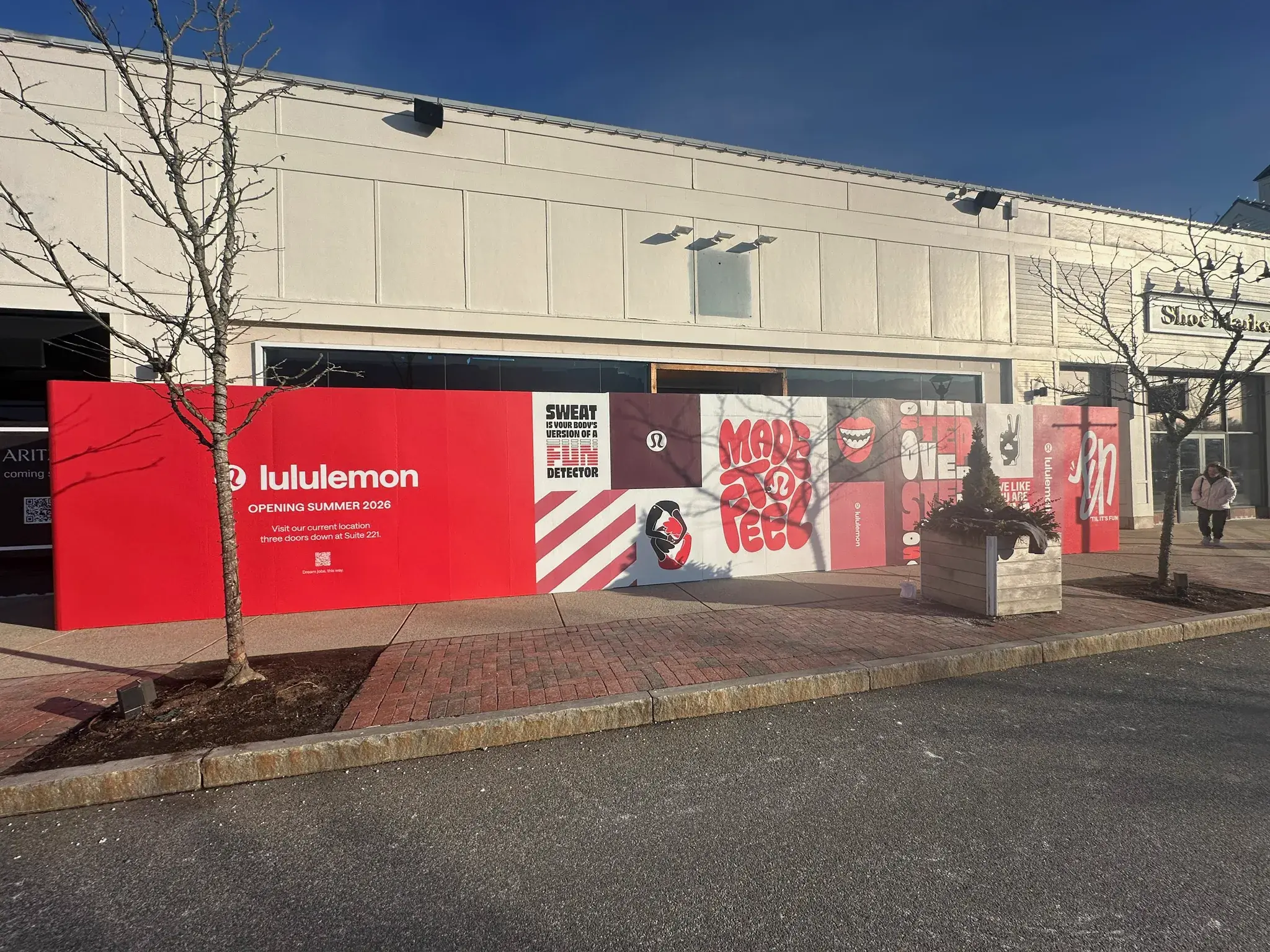 Red lululemon construction hoarding around a vacant storefront