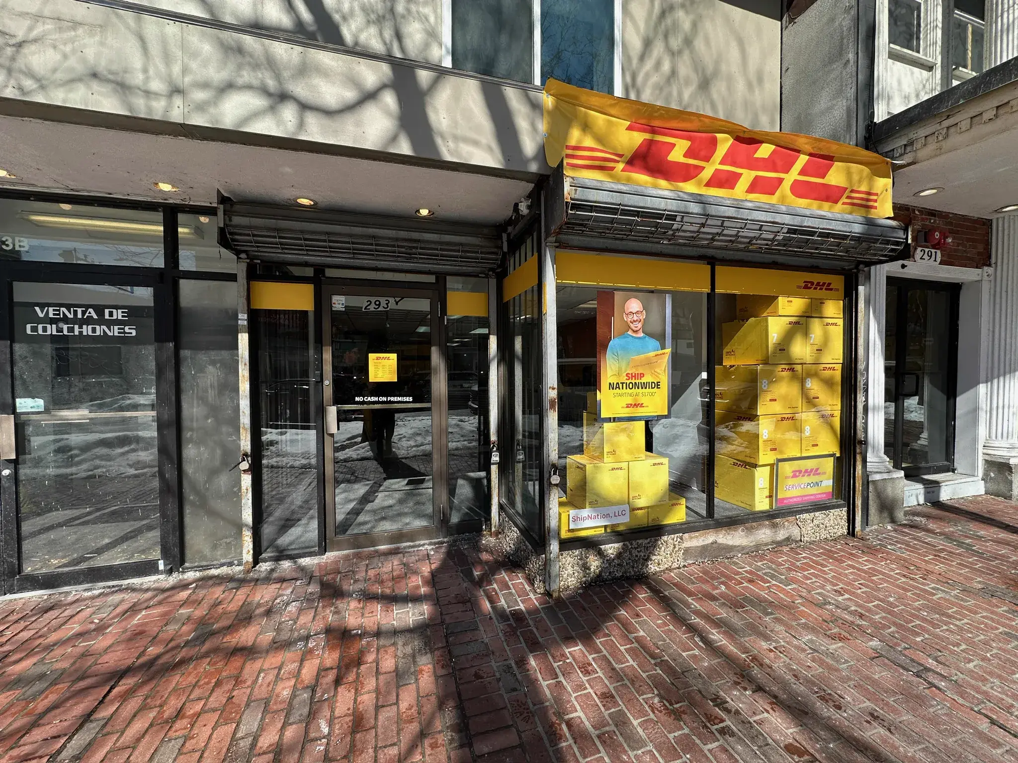 DHL storefront with yellow awning banner and window band graphics