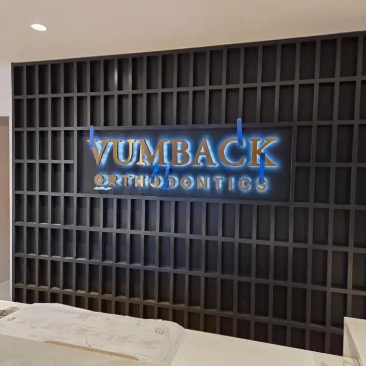 Backlit dimensional lettering on a slatted wall held with painters tape during install