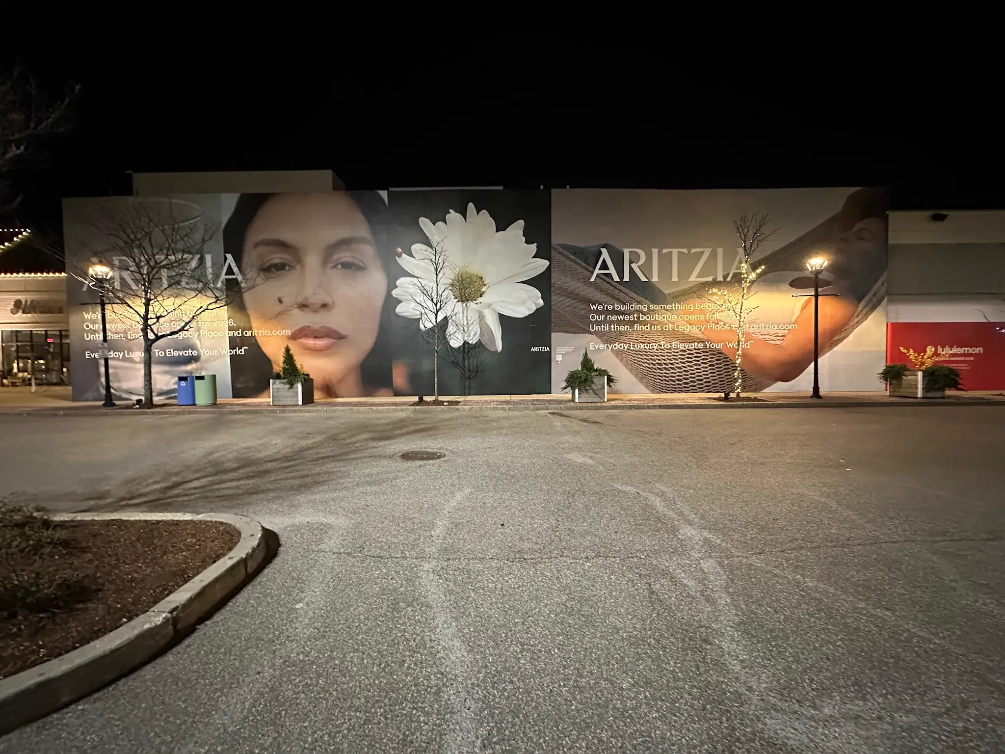 Aritzia hoarding wall with campaign panels photographed at night