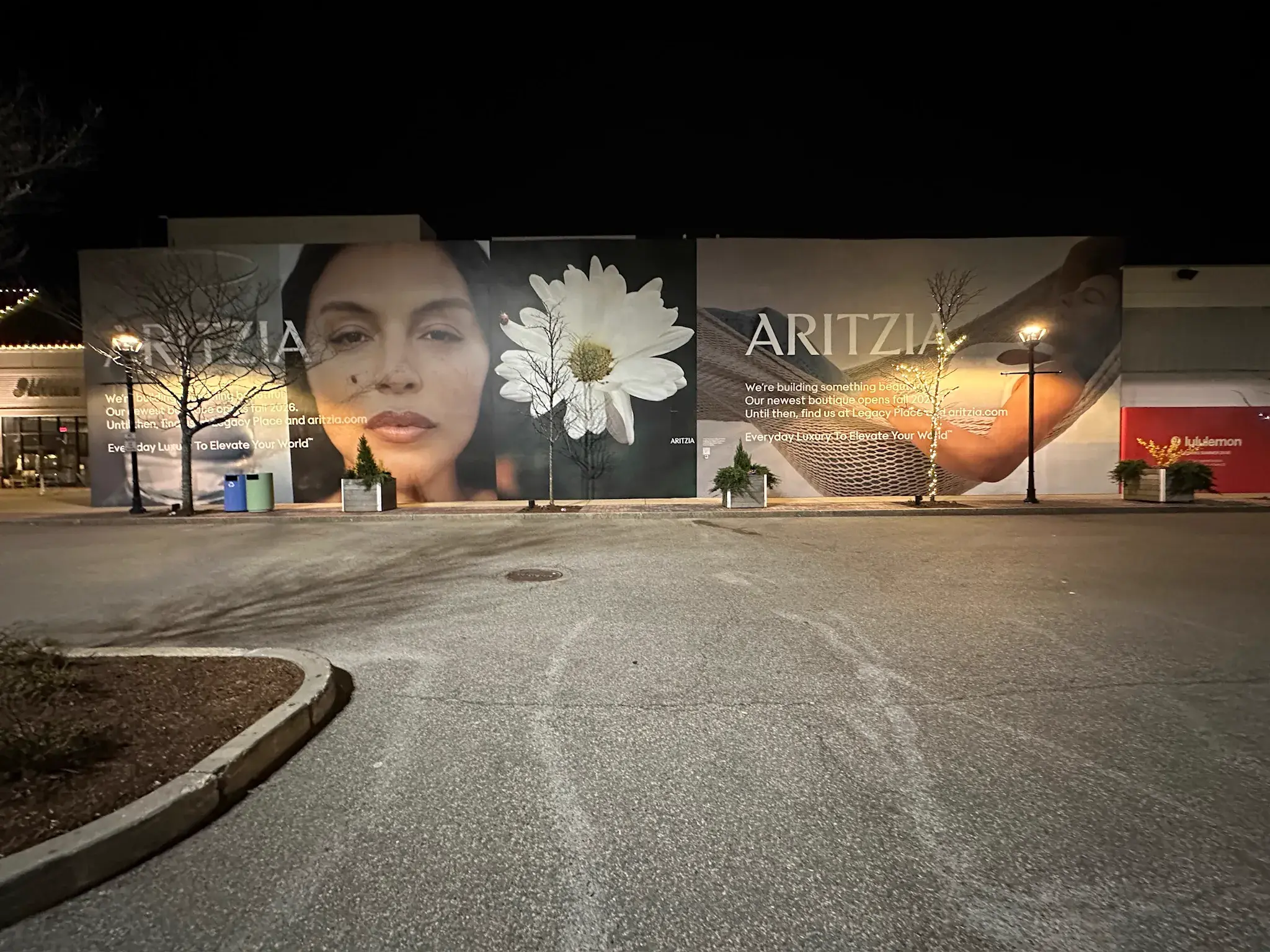 Aritzia hoarding wall with campaign panels photographed at night