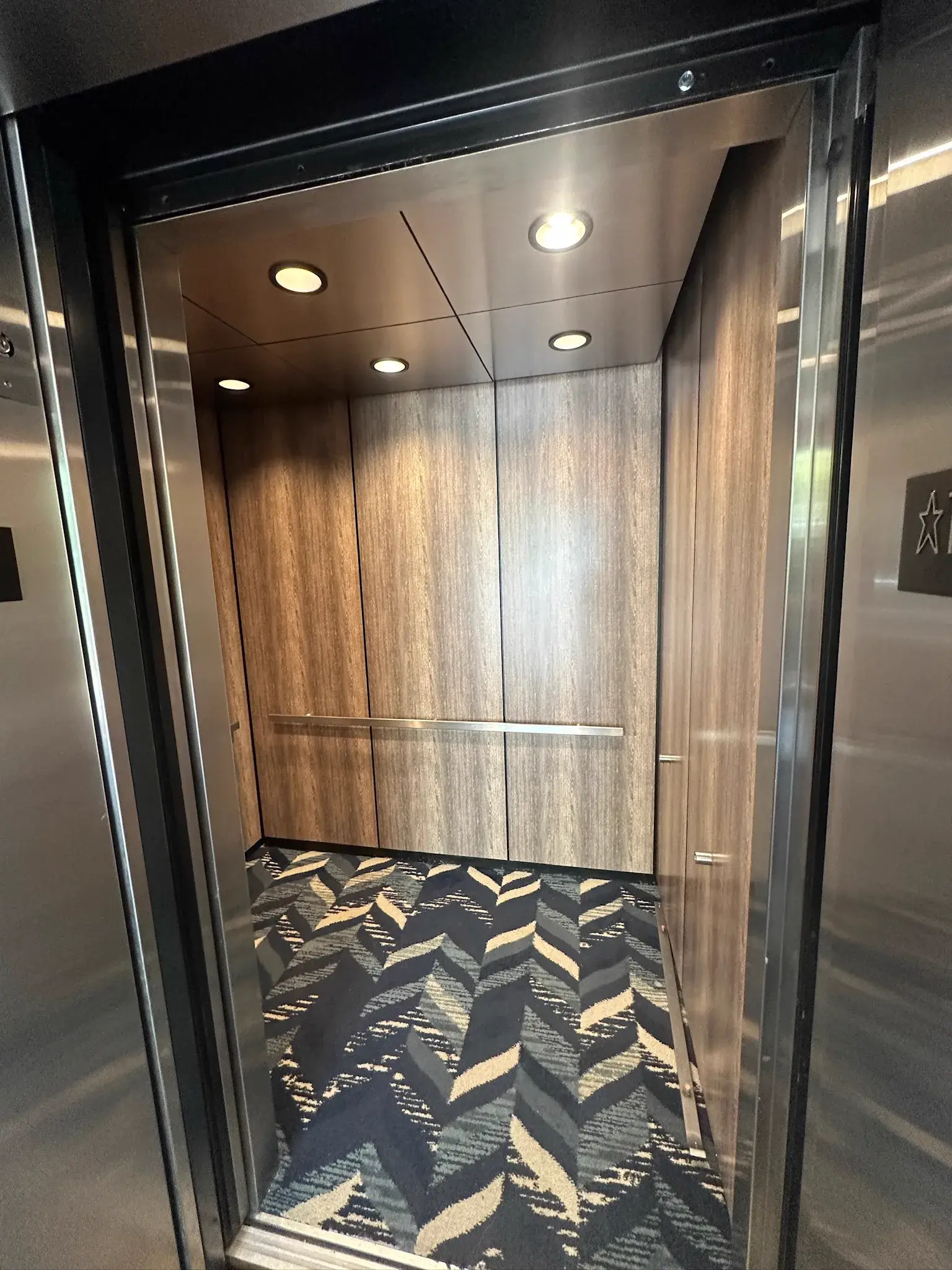 Finished elevator cab with wood grain wrapped panels and handrail