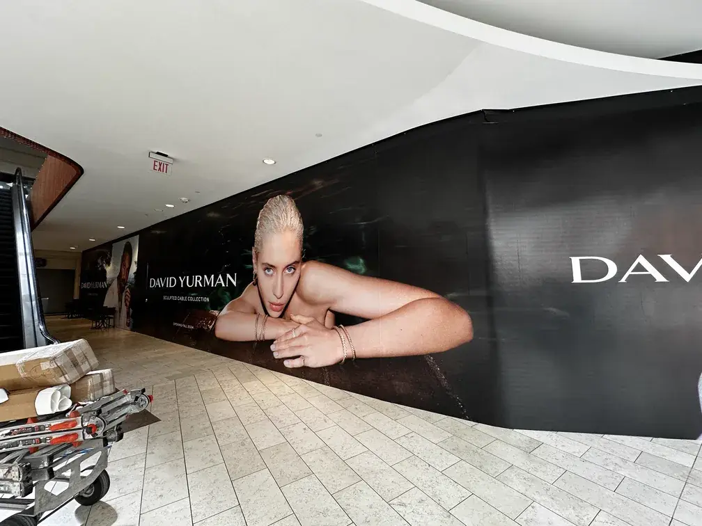 David Yurman curved hoarding graphic beside a shopping centre escalator