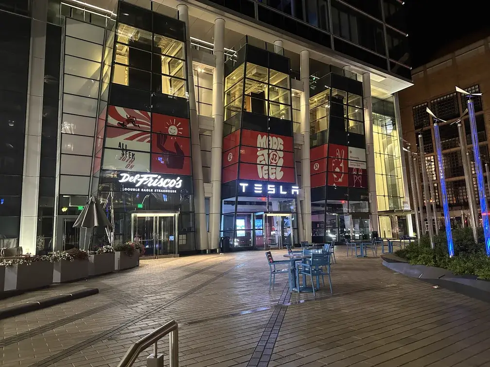 Illuminated multi-tenant building facade with Tesla, Del Frisco’s and lululemon graphics