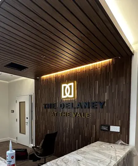 The Delaney at the Vale halo-lit dimensional lettering on a wood slat lobby wall