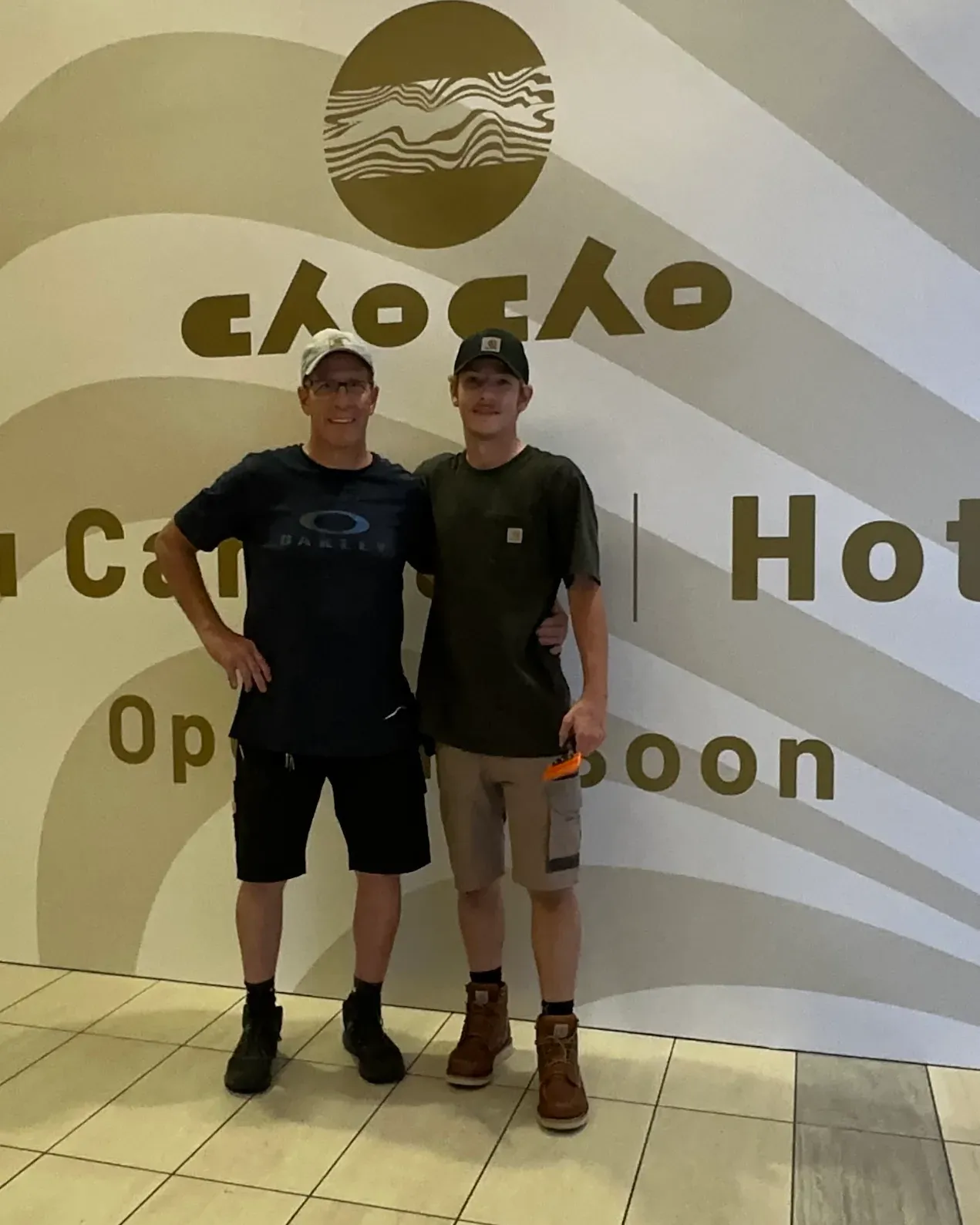 Brian and Ethan Miller of Theory Media standing in front of a wall covering they installed